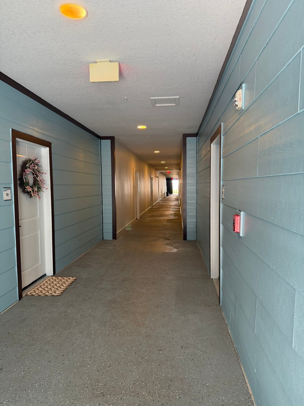 Repainted corridor siding, trim and unit doors at an occupied apartment community in Clearwater, FL